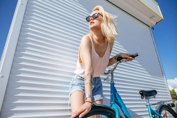 Woman with blond hair near bicycle isolated on white background. - Фото, изображение