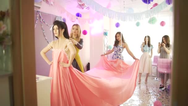 Grupo de cabeleireiro profissional feminino estilista preparando jovem modelo atraente em vestido rosa para celebração de aniversário - Filmagem, Vídeo