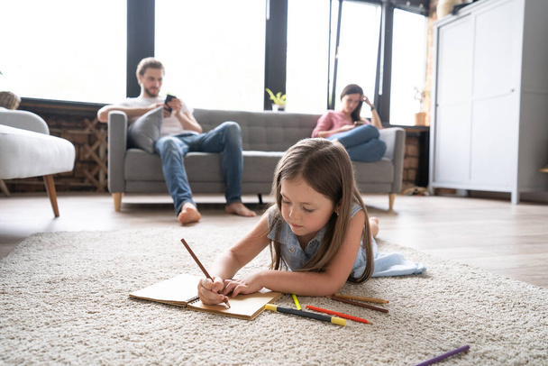 Cute kid girl playing on floor, preschool little girl drawing with colored pencils on paper spending time with family - Foto, Imagen