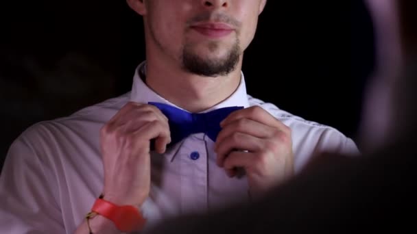 Hezký mladý muž kino film divadelní pracovník s vousy kontrolu jeho modré barvy motýlka na čisté bílé límec košile - Záběry, video