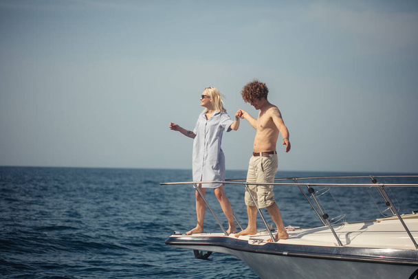 Młoda romantyczna para siedzi na dziobie łodzi, czując się uradowana i zrelaksowana - Zdjęcie, obraz