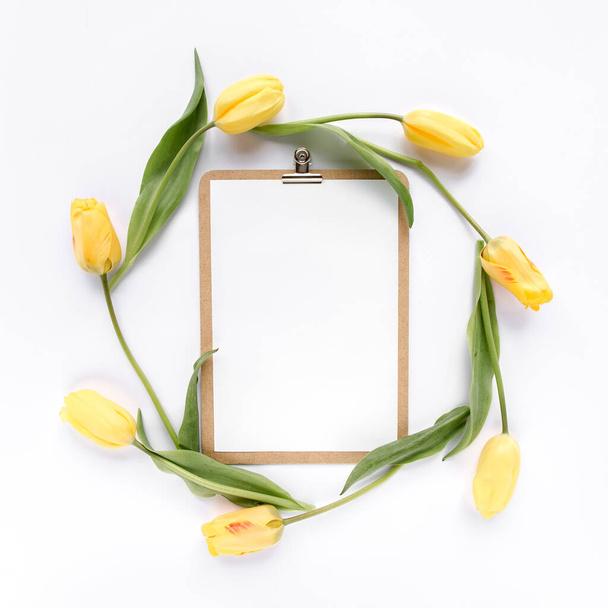 Clipboard mock up with beautiful yellow tulips isolated on white background. Flat lay, top view. Minimalistic office desk. Beauty blog concept. - Foto, Bild