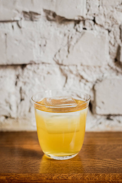 A bright yellow cocktail with ice in a rocks lowball glass - Zdjęcie, obraz