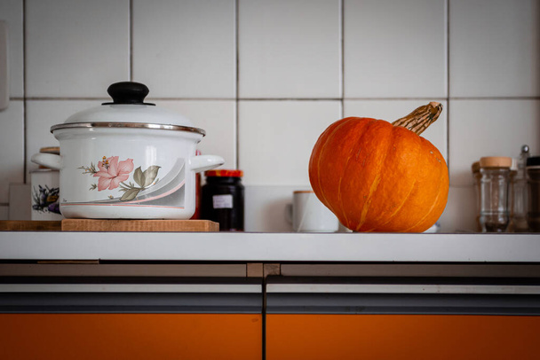 Orange pumpkin lying in the orange kitchen. The pumpkin is prepared for cutting for halloween.  - Foto, imagen