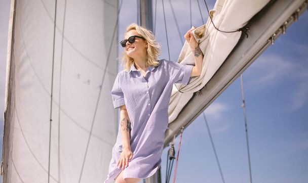 Woman on white yacht in nautical theme in open sea. Blond hair and blue clothes. - Φωτογραφία, εικόνα
