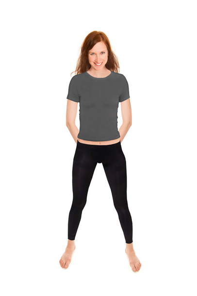 Attractive brunette woman wearing black leggings and a gray shirt, full length portrait isolated in front of white studio background - Photo, Image