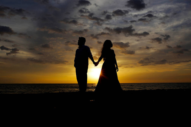 Pár muž a žena se drží za ruce na pozadí západu slunce. - Fotografie, Obrázek