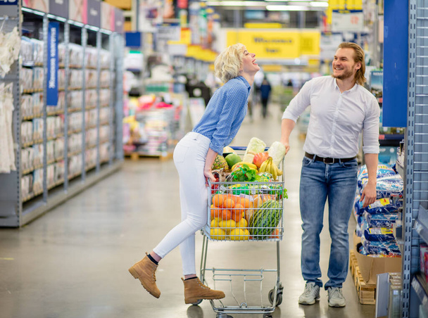 couple enjoying shopping at the supermarket. Woman is about kissing a man - Zdjęcie, obraz