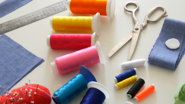 Sewing kit, sewing scissors, bobbins with thread, pincushion with needles, centimeter on a white table background. Sewing workshop, toy factory - Footage, Video