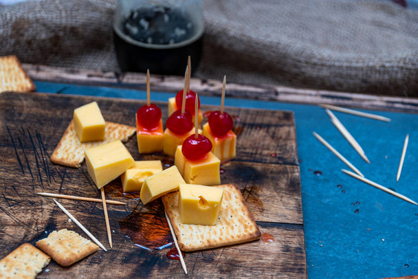 gazdag édes-savanyú cseresznye sajttal és keksszel aperitifnek itallal - Fotó, kép