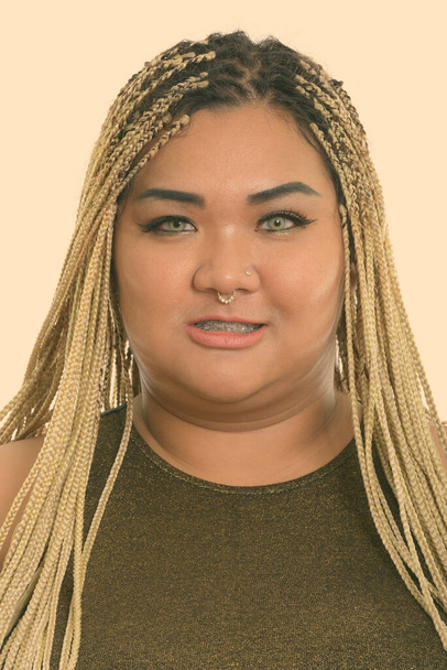 Studio shot of young overweight Asian woman as rebel with dreadlocks isolated against white background - Fotoğraf, Görsel