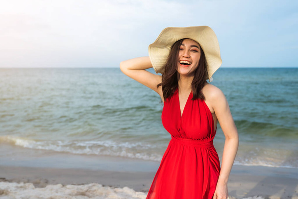 海のビーチで楽しむ赤いドレスの陽気な女性 - 写真・画像