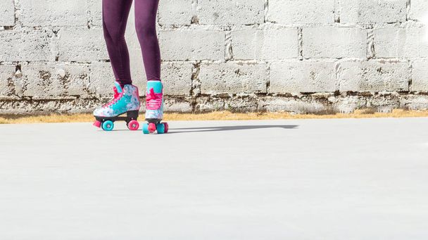 Piernas de una chica con patines de colores sobre un fondo de ladrillo blanco - Foto, imagen