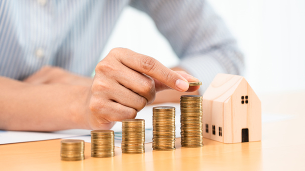 Property investment and house mortgage financial concept, hand of a businessman who is stacking coins for Real estate investment, saving for buying for housing or speculation - Photo, Image