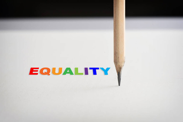 Egyenlőség szó és ceruza fehér papíron fekete háttér. Társadalmi kérdés koncepció és lgbt ötlet - Fotó, kép