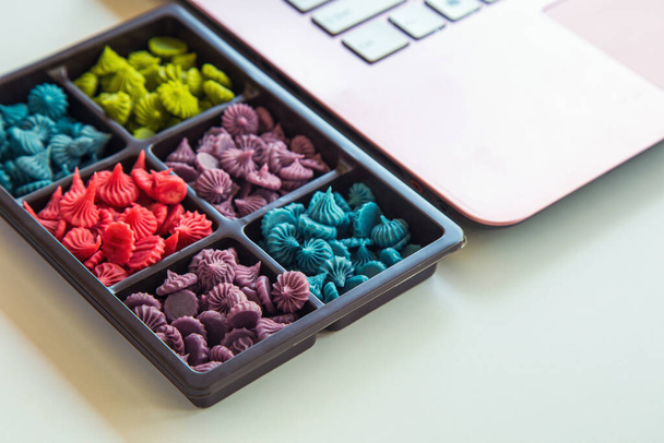 Feche o Allure Thai doces artesanais em uma caixa de plástico marrom ao lado de um laptop rosa em uma mesa branca ao lado da janela. - Foto, Imagem