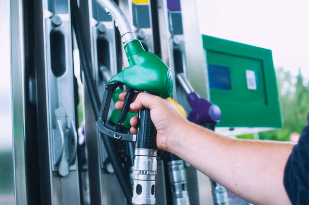 Man holds a refueling gun in his hand for refueling cars. Gas station with diesel and gasoline fuel close-up - Photo, Image