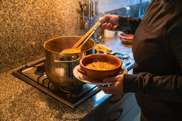 vrouw serveert locro, typisch Argentijns eten op handgemaakte keramische platen. - Foto, afbeelding