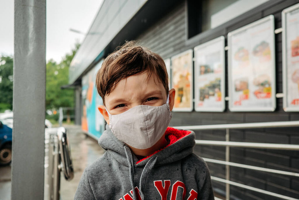 保護マスクの少年がスーパーに入ってくる。スーパーマーケットでのcovid-19コロナウイルスから子供を守る. - 写真・画像