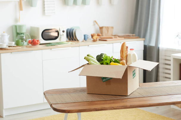 Εικόνα φόντου από χαρτόνι κουτί με φαγητό σε ξύλινο τραπέζι σε minimal κουζίνα εσωτερικό, αντίγραφο χώρου - Φωτογραφία, εικόνα