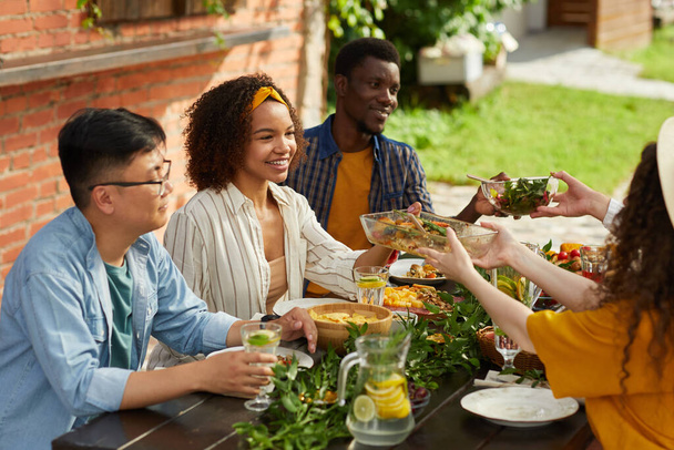 Grupo multi-étnico de pessoas que compartilham comida enquanto desfrutam de jantar com amigos e familiares ao ar livre na festa de verão, espaço de cópia - Foto, Imagem
