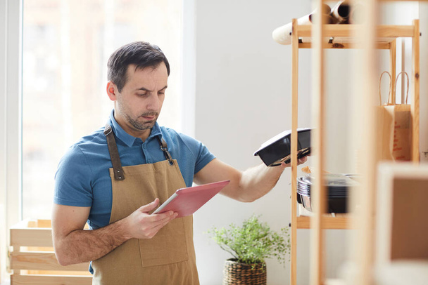 Waist up portrait of mature man wearing apron using digital table while doing inventory in food delivery service, copy space - Photo, Image