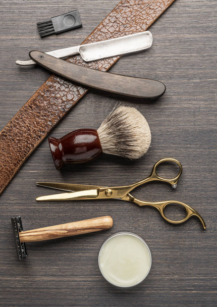 Classic grooming and hairdressing tools on wooden background. Top view on barbershop instruments  laying on dark wooden table. - 写真・画像