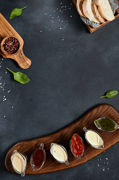 Assortment sauce on wooden board. Black slate table top view. Bread and Pepper overhead. Copy Space - Photo, image