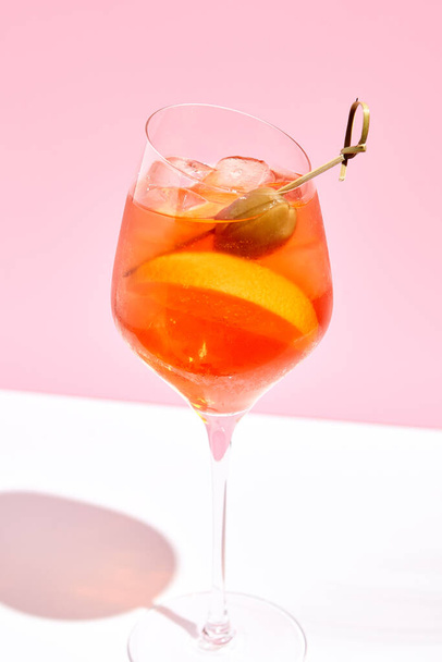Aperol spritz on pink background. Pink and white background. Hard light and shadow - Фото, зображення
