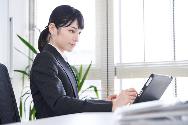 Una donna giapponese che usa un tablet nel suo ufficio per convertire documenti cartacei in dati - Foto, immagini