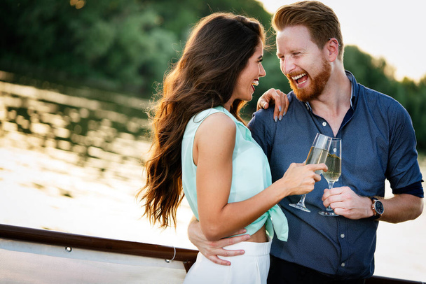 Summer holidays and dating concept. Happy beautiful romantic couple in love hugging with champagne - Photo, Image