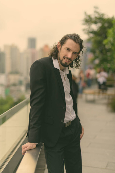 Portrait of handsome businessman with long curly hair against view of the city in Bangkok, Thailand - Fotografie, Obrázek