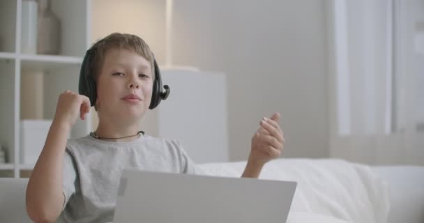 freche kleine Junge chattet online per Laptop, aktive und positive Kind, sitzt zu Hause am Wochenende, Portrait - Filmmaterial, Video
