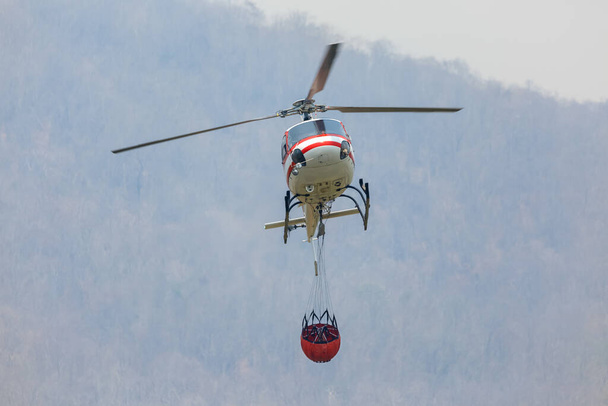 Požární vrtulník nesoucí kbelík na vodu - Fotografie, Obrázek