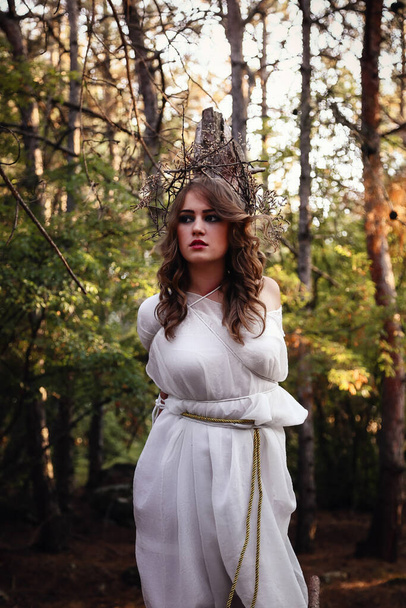 Sonbahar ormanında uzun beyaz elbiseli, gizemli gotik kadın. Karanlık fantezi yaratığı, bir cadı için şenlik ateşi - Fotoğraf, Görsel