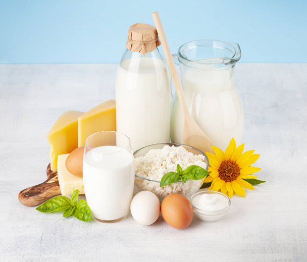 Vari prodotti lattiero-caseari. Latte, formaggio, casetta, panna acida. Davanti a sfondo blu - Foto, immagini