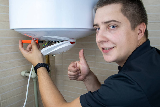 Boiler repairman shows a thumbs up. A smile and a like says that a professional craftsman will do the job efficiently. Technical assistance and support concept - Photo, Image