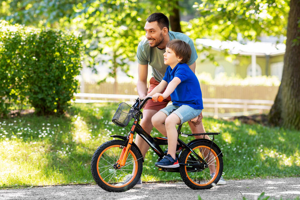 Vater bringt kleinem Sohn Fahrradfahren im Park bei - Foto, Bild