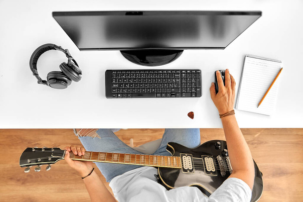 young man with computer and guitar at table - Photo, image