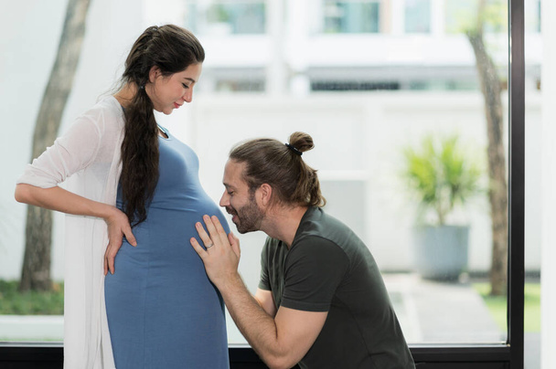 Hombre de barba guapo besándose con su esposa embarazada. Concepto de familia feliz. - Foto, imagen