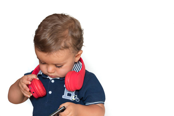 lapsi katselee videoita matkapuhelimella punaiset kuulokkeet ja tummansininen paita - Valokuva, kuva