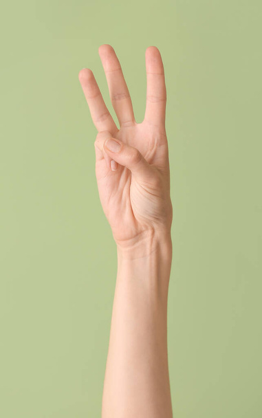 Рука показывает букву W на цветном фоне. Алфавит жестового языка - Фото, изображение
