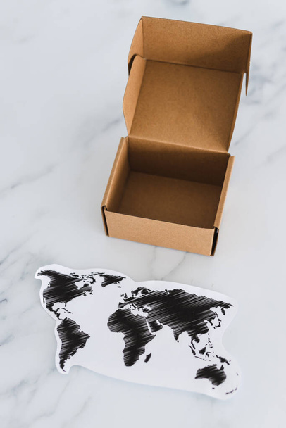 concept of global trade and worldwide deliveries, miniature postal parcel next to world map - Foto, immagini