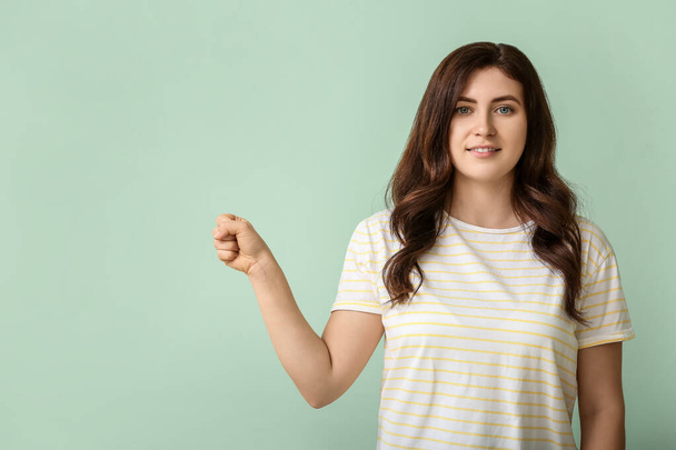 Молода глуха жінка використовує мову жестів на кольоровому фоні
 - Фото, зображення