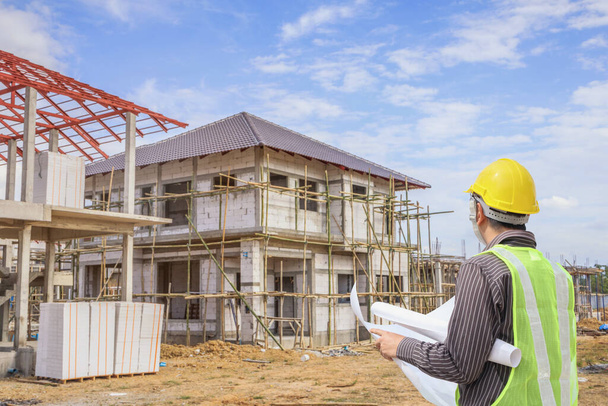 Professional engineer architect worker with protective helmet and blueprints paper at house building construction site background - Фото, зображення