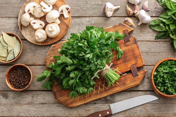 Board with fresh parsley, mushrooms and spices on wooden background - Photo, image