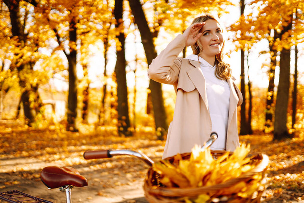 Φθινοπωρινή γυναίκα στο πάρκο. Ευτυχισμένη νεαρή γυναίκα ποζάρουν με ποδήλατο στο δάσος του φθινοπώρου. - Φωτογραφία, εικόνα
