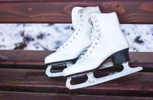 white figure skates lie on a wooden bench, active winter recreation, healthy lifestyle - Photo, Image