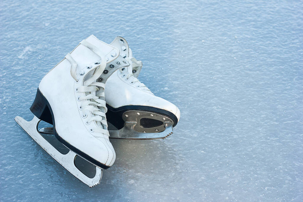 old white figure skates lie on ice, winter outdoor activities, sports health in winter, space for text - Photo, Image