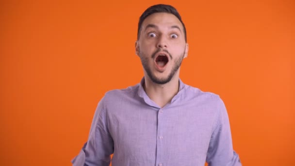 Fiatal izgatott férfi megérinti fej kezével narancssárga stúdió háttér - Felvétel, videó